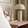 A bedside table with a lamp, candle, vase with flowers, and perfume. Náhled obrázku produktu