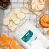 Sliced fruits and vegetables are arranged on a checkered cloth, with a package of vacuum seal bags in the foreground. Náhled obrázku produktu