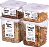 Four clear plastic food storage containers with white lids, stacked in a 2x2 arrangement. Each container is filled with different food items: cookies, cereal, grains, and pasta. Labels are visible on the front of each container. Produktbild-Vorschau