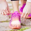 A person tying the laces of a pink running shoe, with a clear gel toe separator visible inside the shoe. Podgląd zdjęcia produktu