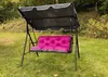 A garden swing with a pink cushion is set up on a grassy lawn with trees and foliage in the background. Produktbild-Vorschau