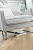 A steam cleaner is being used to clean the floor under a gray armchair. Anteprima dell’immagine prodotto