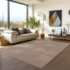 A modern living room with a large window, sofa, plants, and a rug.
