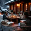 A family is having dinner outdoors in the snow, with a heater in the foreground. Produktbild-Vorschau