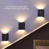 Three solar-powered wall lights are mounted on a wall, illuminating the area with upward and downward beams of light. The image also shows a staircase railing in the foreground. Produktbild-Vorschau