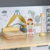 A dollhouse bedroom scene with a bed, a doll, and a lamp. Produktbild-Vorschau