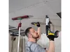 A man is installing drywall on a ceiling using a power drill and a drywall support pole. Náhľad obrázku produktu