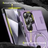 A close-up, angled view of a purple smartphone case with a ring stand and camera cover, placed on a dark, textured surface. Náhled obrázku produktu