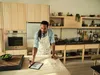 A man is in a kitchen, preparing dough and looking at a tablet. Produktbild-Vorschau