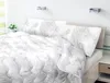 A neatly made bed with a white comforter and pillows featuring a floral pattern. Náhled obrázku produktu
