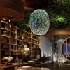 A modern interior with a unique pendant light, shelves filled with items, and seating areas. Náhled obrázku produktu