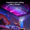 A young woman lies in bed looking up at a projector displaying a colorful, tunnel-like light show on the ceiling. Náhled obrázku produktu