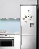 A kitchen scene with a refrigerator adorned with several small photo magnets. Produktbild-Vorschau