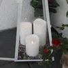 Three white LED candles are placed inside a white lantern with gravel at the base. Red roses and green leaves are visible to the right. Produktbild-Vorschau
