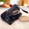 A black manual bread slicer with two slices of bread on a countertop. Náhled obrázku produktu