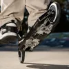 A person is riding a stunt scooter in an outdoor skate park. Náhled obrázku produktu