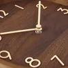 A close-up view of a wooden wall clock with gold-colored numbers and hands. Voir les images du produit