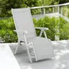 A white and gray outdoor lounge chair is shown on a light gray patio with green foliage in the background. Produktbild-Vorschau
