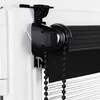 Close-up of a black roller blind mechanism attached to a white window frame. Náhled obrázku produktu