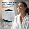 A woman in a bathrobe smiles while a white bathroom cabinet is displayed. Produktbild-Vorschau