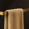 A close-up of a tan towel hanging on a gold towel rack against a black background. Náhled obrázku produktu