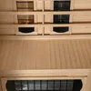 Interior view of a wooden sauna cabin, showing heating elements and wooden slats. Produktbild-Vorschau