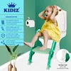 A young child is sitting on a green toilet training step stool next to a toilet. Produktbild-Vorschau