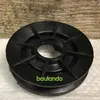 A black pulley is shown against a textured wooden background and a white surface. Produktbild-Vorschau