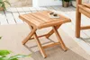 A wooden side table on a patio with a rug and plants. Produktbild-Vorschau