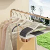 Several clothes hangers with clothes hanging on them are displayed on a rack. Voir les images du produit