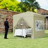 A man stands next to a beige pop-up gazebo set up on a lawn, with a table and chairs inside. Náhled obrázku produktu