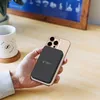 A hand holding a smartphone with a power bank attached, on a wooden desk. Produktbild-Vorschau