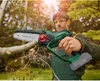 A man is using a cordless chainsaw to cut a branch in an outdoor setting with trees and foliage in the background. Produktbild-Vorschau
