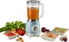 A retro-style blender with a clear pitcher filled with orange liquid, surrounded by fresh vegetables and bowls of soup. Anteprima dell’immagine prodotto