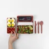 A bento box lunch with boiled eggs, cherry tomatoes, and a salad, along with cutlery, laid out on a white background. Podgląd zdjęcia produktu