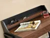 A close-up view of a desk shelf with a magazine, keys, sunglasses, and a glass of drink. Náhled obrázku produktu