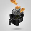 A black air fryer with a basket and rack, with fried chicken drumsticks falling into it, and oil droplets. Produktbild-Vorschau