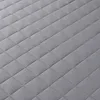 A close-up, angled view of a quilted gray blanket. Produktbild-Vorschau