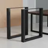 Two black metal table legs are shown in a studio setting with a beige and gray background. Produktbild-Vorschau