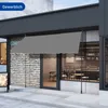 A grey awning is extended over the entrance of a modern cafe or shop. Anteprima dell’immagine prodotto