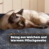 A Siamese cat is resting on a dark gray, plush surface, with text overlay describing the material. Produktbild-Vorschau