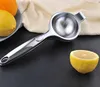 A manual citrus juicer is placed on a dark surface next to a halved lemon, with whole lemons and an orange in the background. Produktbild-Vorschau