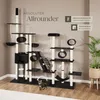 A large, multi-level cat tree with various platforms, tunnels, and scratching surfaces, featuring two cats interacting with it. The background is a plain wall with some marketing text and icons. Náhled obrázku produktu