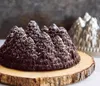 A chocolate bundt cake shaped like a pine forest, dusted with powdered sugar, sits on a wooden board. A silver bundt pan is visible in the background. Anteprima dell’immagine prodotto