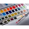 A close-up view of a watercolor paint set with brushes and water droplets. Produktbild-Vorschau