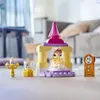 A LEGO DUPLO set featuring characters from Disney's Beauty and the Beast, including Belle, Lumiere, Mrs. Potts, and Cogsworth, arranged on a wooden floor with a blurred living room background. Podgląd zdjęcia produktu