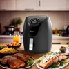 A black air fryer is displayed on a kitchen counter, surrounded by various food items like steak, salmon, fries, and juice. Produktbild-Vorschau
