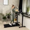 A woman is working on a laptop while standing on a treadmill next to a standing desk in a home office setting. Náhľad obrázku produktu