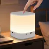 A hand is touching a white LED night light on a wooden nightstand next to a laptop. Produktbild-Vorschau