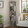 A corner bookshelf filled with books and decorative items, next to a window with plants and a sofa. Anteprima dell’immagine prodotto